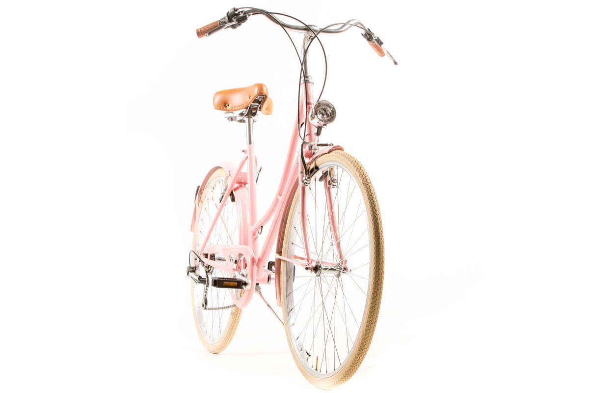 Manillar de la rueda delantera y cesta de una bicicleta femenina cerca de  una puerta de metal marrón